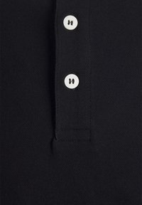 Tissu noir texturé avec deux boutons blancs alignés verticalement sur une patte de boutonnage, partie d'une chemise à col.