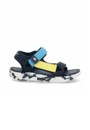Sandal de color navy y azul con correas ajustables y acentos amarillos, y una plantilla negra texturizada. Suela blanca con un patrón abstracto en negro.
