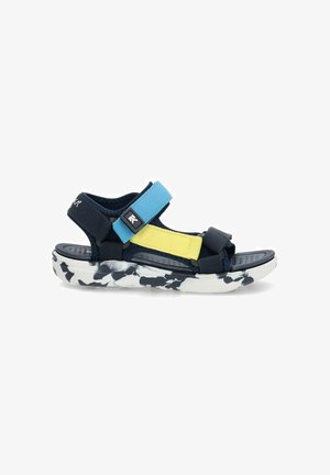Sandal de color navy y azul con correas ajustables y acentos amarillos, y una plantilla negra texturizada. Suela blanca con un patrón abstracto en negro.