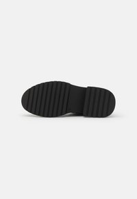 Talpa de cauciuc neagră cu un model texturat și stratificat. Formă ovală cu un profil plat. Design minimalist, fără culori sau accente suplimentare.