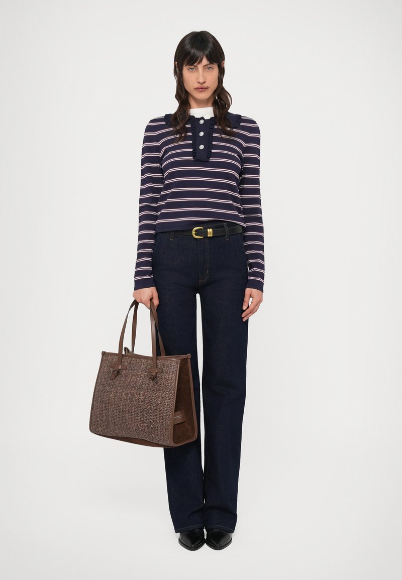 Prúžkované tričko s dlhým rukávom v námorníckej modrej a ružovej farbe, s vysokým golierom na gombíky, kombinované s tmavými džínsami. Hnedá textúrovaná taška cez rameno s rúčkami.