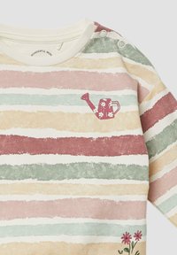 Maglietta a maniche lunghe a righe in morbido cotone, caratterizzata da colori pastello: rosa, verde e crema, con una piccola grafica di un annaffiatoio e accenti floreali.
