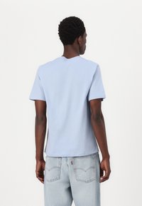 Ανοι�χτό μπλε βαμβακερό μπλουζάκι με κοντά μανίκια, στρογγυλή λαιμόκοψη και χαλαρή εφαρμογή, σε συνδυασμό με ανοιχτού χρώματος τζην παντελόνι που διαθέτει ραμμένες πίσω τσέπες.