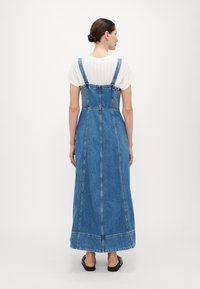 Denim-maksimekko säädettävillä olkaimilla, muotoillulla vartalo-osalla, jossa on joustava rypytys, ja täyspitkä, suora leikkaus vaaleansinisessä värissä.