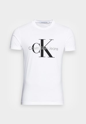 Valkoinen puuvillateeppari, jossa on musta "CK"-logo ja "Calvin Klein Jeans" -teksti, lyhyet hihat ja klassinen pyöreä kaula-aukko.