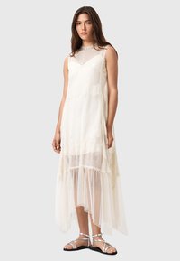 Spitzenkleid in Off-White mit hohem Kragen, ärmellosem Design, schichtgemäßem, durchscheinendem Rock mit strukturierten Akzenten und fließender Silhouette.