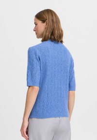 Helles blaues Kurzarm-Sweatshirt mit einem strukturierten, gestrickten Muster. Verfügt über einen gerippten Rundhalsausschnitt und Saum, hergestellt aus weichem, atmungsaktivem Material.