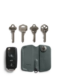 Clé de voiture noire avec trois boutons, quatre clés argentées et un porte-clés en cuir vert foncé avec un bouton-pression et des bords surpiqués.