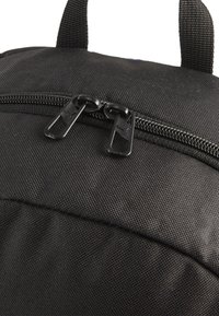 Zaino nero con tessuto testurizzato. Presenta due tirazip neri e un manico superiore per il trasporto. Design semplice senza schemi visibili.
