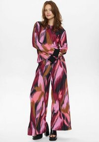 Garš sleeve top un plaša kāju bikses no plīšu auduma ar spilgtiem abstraktiem rakstiem rozā, melnā un brūnā krāsā.