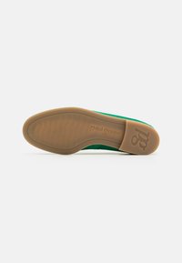 Scarpa in suede verde con suola piatta in gomma marrone chiaro. Presenta dettagli di marca sul tallone. Texture liscia, design minimalista.