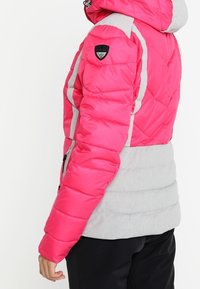 Padded jacket featuring a bright pink upper section, gray lower section, and reflective accents. Includes a hood and zippered pockets.