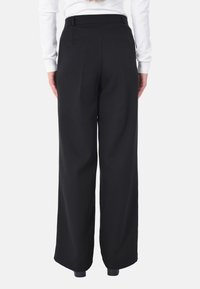 Pantaloni larghi neri con una texture liscia, caratterizzati da un alto punto vita, due tasche posteriori e dettagli con pieghe pressate lungo le gambe.