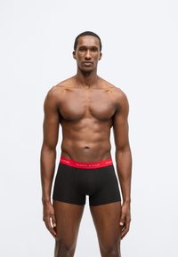 Mustad bokserid punase Tommy Hilfigeri vöökohaga. Kangas tundub sile ja disain on vormi järgiv klassikalise lõikega.