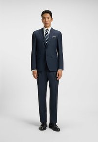 Mörkblå kostym med en strukturerad mönster, en vit skjorta och en randig slips. Har en enkel knappstängning och en slim fit-design.