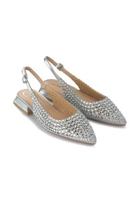 Zapatos plateados tipo slingback con punta puntiaguda, adornados con piedras brillantes; cuentan con un tacón bajo y un diseño de corte en los laterales.