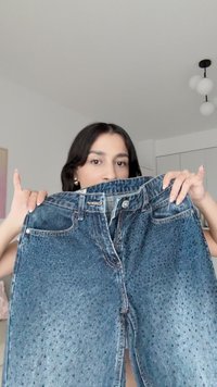 Denimjeans i en blekt blå nyans, med en något sliten textur, glittrande detaljer, fem fickor och dragkedja fram.