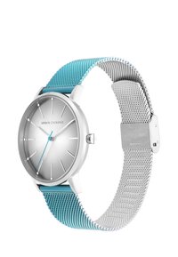 Reloj analógico plateado con esfera redonda, correa de malla turquesa y fondo de malla plateado. Presenta marcadores de horas minimalistas y manecillas azules.