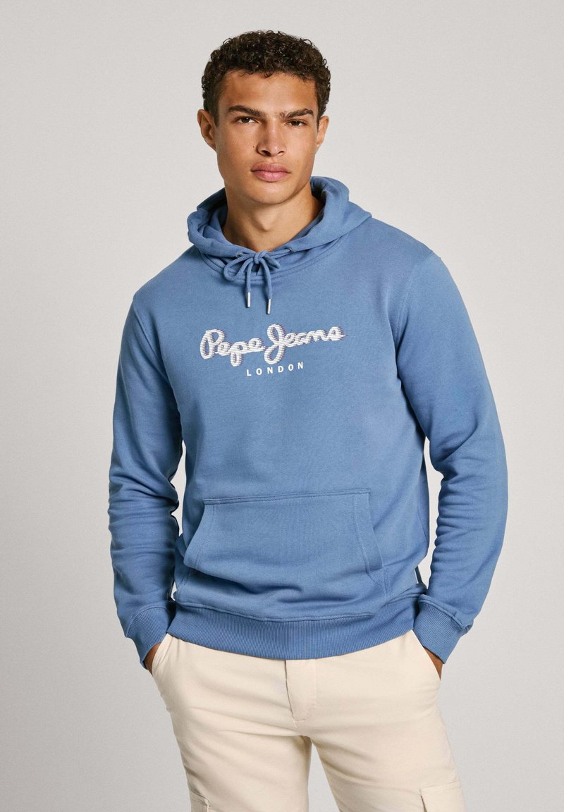 Sudadera de algodón azul con bolsillo frontal, capucha con cordón y logotipo de "Pepe Jeans London" en texto cursivo blanco. Acabado de tejido texturizado.