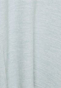 Tissu tricoté gris clair doux avec une texture fine et régulière et de légers plis verticaux.