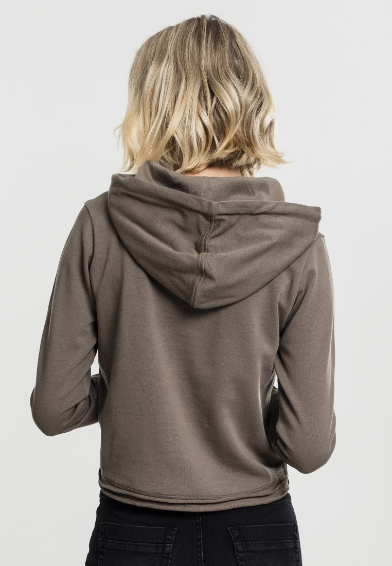 Brun cropped hoodie med en myk tekstur, med en stor hette og sømdetaljer. Bærer svarte jeans, viser bakvinkel.