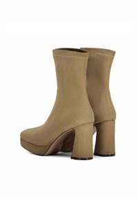 Bottines beige avec une finition en daim lisse ; semelle compensée et talons épais ; bout arrondi et design supérieur en tricot sans couture.
