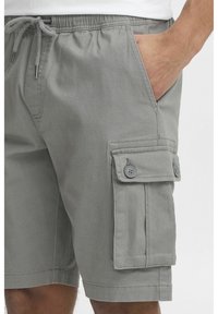 Graue Cargo-Shorts aus weichem Stoff, mit einem elastischen Bund mit Kordelzug, Seitentaschen und einer großen, knöpfbaren Cargo-Tasche.