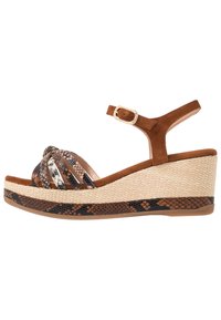 Sandalias de cuña con una correa de tobillo de ante marrón y plataforma de yute trenzado. La parte superior presenta un diseño de estampado de serpiente en tonos marrón, beige y negro.