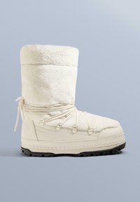 Hvid isoleret vinterstøvle med overdel i imiteret pels, snøredetaljer og tekstureret gummisål. Har rundet tå og polstret manchet.