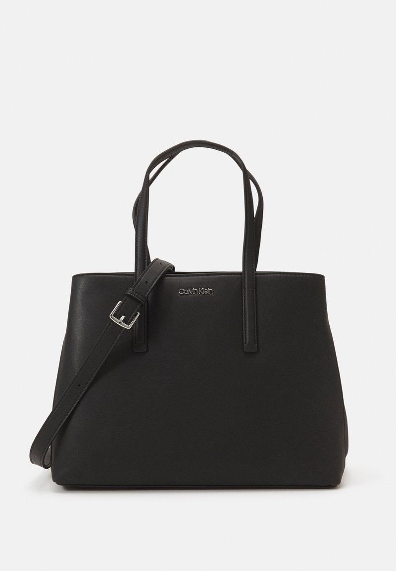 Sac cabas noir Calvin Klein avec deux bretelles d’épaule et une bandoulière réglable sur fond blanc.