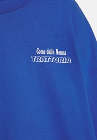 Blauw katoenen T-shirt met witte tekst, "Come dalla Nonna TRATTORIA," duidelijk gedrukt op de voorkant. Korte mouwen, standaard pasvorm.