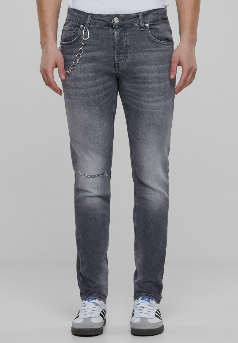 Szürke farmerruha, slim fit szabással, térdnél egy szakítással, finom kopásokkal és fémtartó lánccal a zseben.