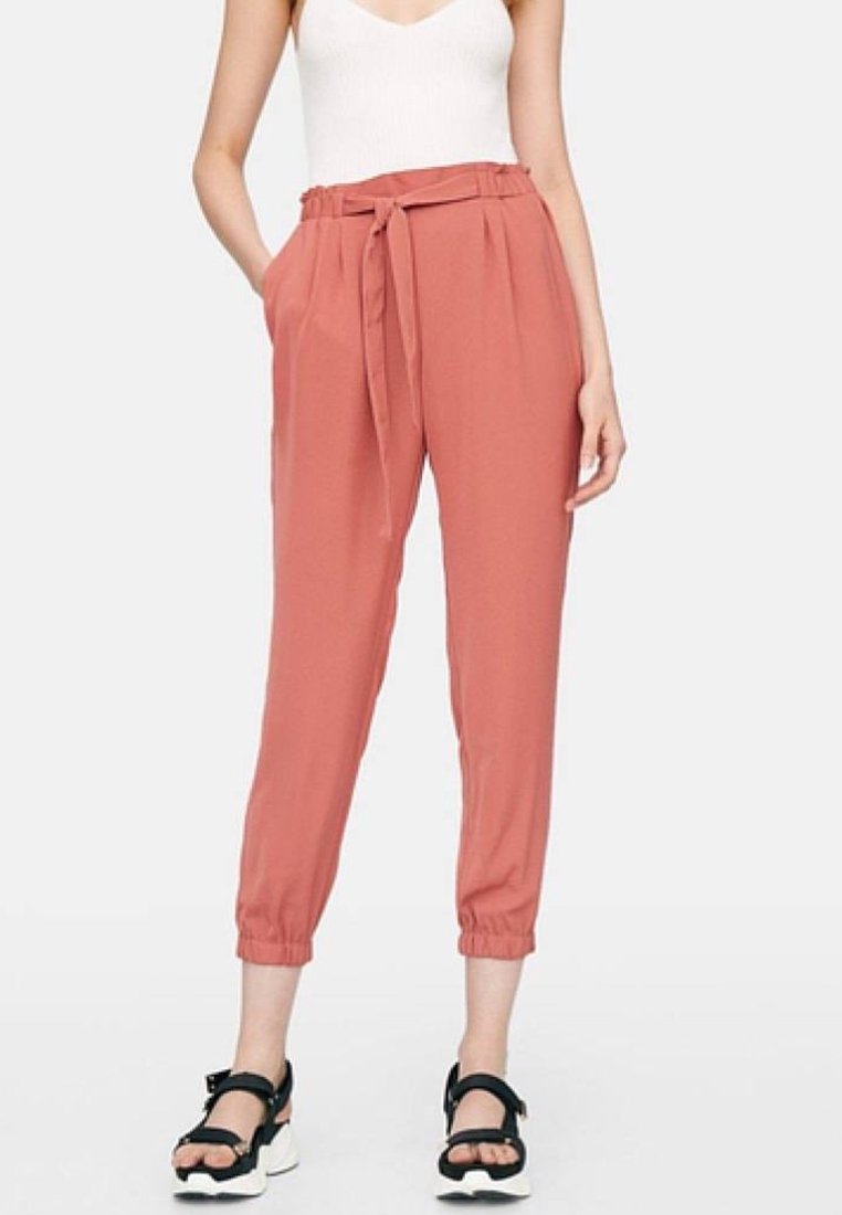 Lätta, avsmalnande byxor i en mjuk korallfärg med ett tygbälte i midjan, elastiska muddar och sidofickor.Matcherat med svarta sandaler.
