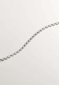 Collar de cadena de plata que presenta eslabones interconectados en forma ovalada y redonda, textura suave y un brillo uniforme sobre un fondo claro.