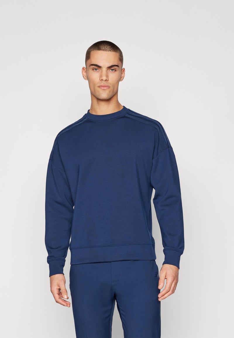Felpa blu navy con collo a giro, maniche lunghe, polsini e orlo a costine, caratterizzata da cuciture sulle spalle con un sottile motivo testurizzato.