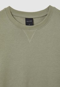 Olivgrüner Sweater mit Rundhalsausschnitt, gerippten Bündchen und Kragen. Verfügt über ein dreieckiges Nähdetail am Kragen und ein schwarzes Etikett im Inneren.