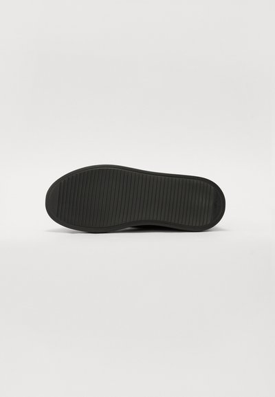 Talpa de pantof neagră cu textură nervată, margine rotunjită și design plat. Materialul pare a fi cauciuc cu o finisare netedă.
