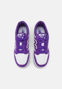 Scarpe da ginnastica viola e bianche con tomaia in tessuto testurizzato, chiusura con lacci, punta perforata e logo visibile sulla linguetta.