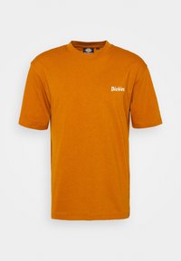Short-sleeve T-shirt in mustard yellow cotton. Features a crew neck and small white "Dickies." logo on the left chest. Lightweight fabric.
