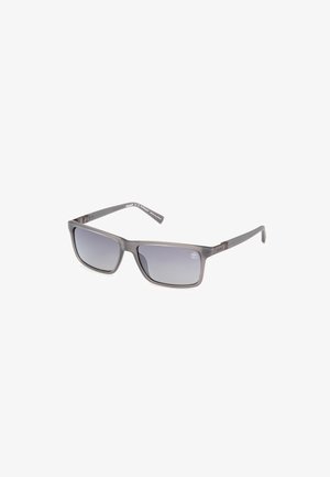 Gafas de sol grises con un marco rectangular, lentes de degradado y un diseño elegante y ligero. Presenta una sutil marca en las patillas.