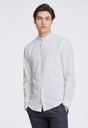 Camisa de lino blanca de manga larga con cuello alzado, botones frontales y un bolsillo; tejido texturizado y ligero.