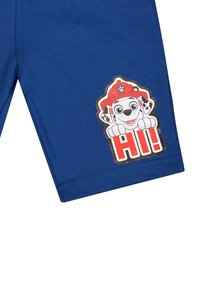 Blaue Baumwollshorts mit einem großen Motiv eines Cartoon-Hundes in einem Feuerwehrhelm mit roten Akzenten und dem Text "AH!" an der Seite.
