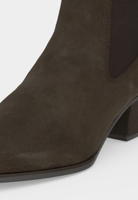 Bottine en daim marron foncé pour femme avec un panneau latéral élastique et un petit talon bloc, vue de face et de côté.