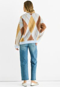 Knitted sweater in pastel blue with brown and yellow diamond pattern, relaxed fit, ribbed cuffs and hem, paired with light blue jeans and silver flats.