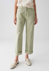 Jean taille haute vert clair avec une coupe décontractée, bas roulés et poches avant. Fabriqué à partir d'un tissu en coton texturé.