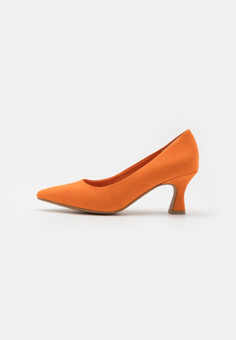 Escarpin à talon aiguille en suede orange avec bout pointu et talon incurvé de hauteur moyenne. Texture lisse et couleur unie sur toute la chaussure.