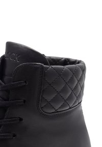 Botină neagră din piele cu guler păturat matlasat, șireturi negre și un branding subtil debossat pe limbă.