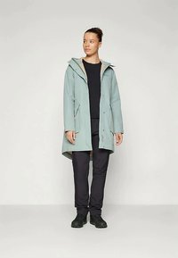 Gaiši zils ūdensnecaurlaidīgs mētelis ar kapuci, ar bēšu oderi un priekšējiem pogām. Pāris ar melniem biksēm un izturīgām melnām kurpēm.