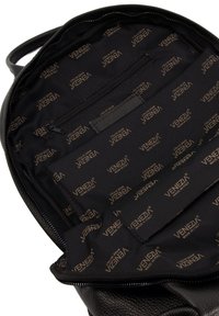 Intérieur d'un sac à dos en cuir noir avec un motif texturé. Comprend une poche zippée et une doublure de marque avec "VENEZIA" en doré.