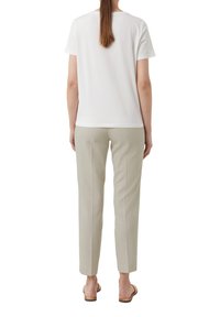 White short-sleeve t-shirt paired with light grey tailored pants, featuring a smooth texture and straight cut, with open-toe sandals.